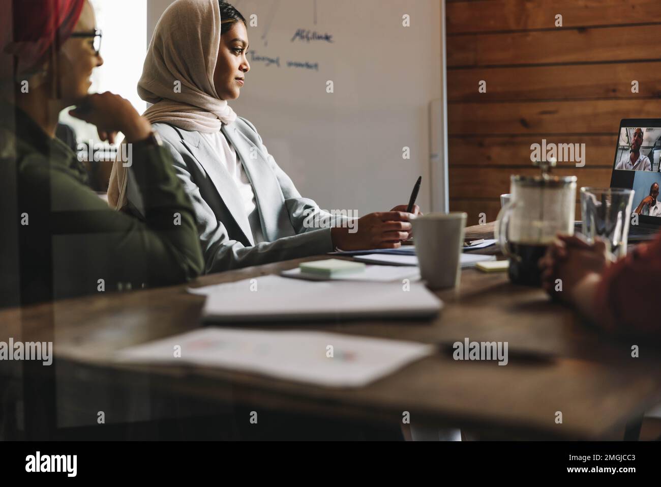 Femmes entrepreneurs assistant à une réunion en ligne dans un bureau moderne. Femmes d'affaires musulmanes ayant une vidéoconférence avec leurs associés d'affaires moi Banque D'Images