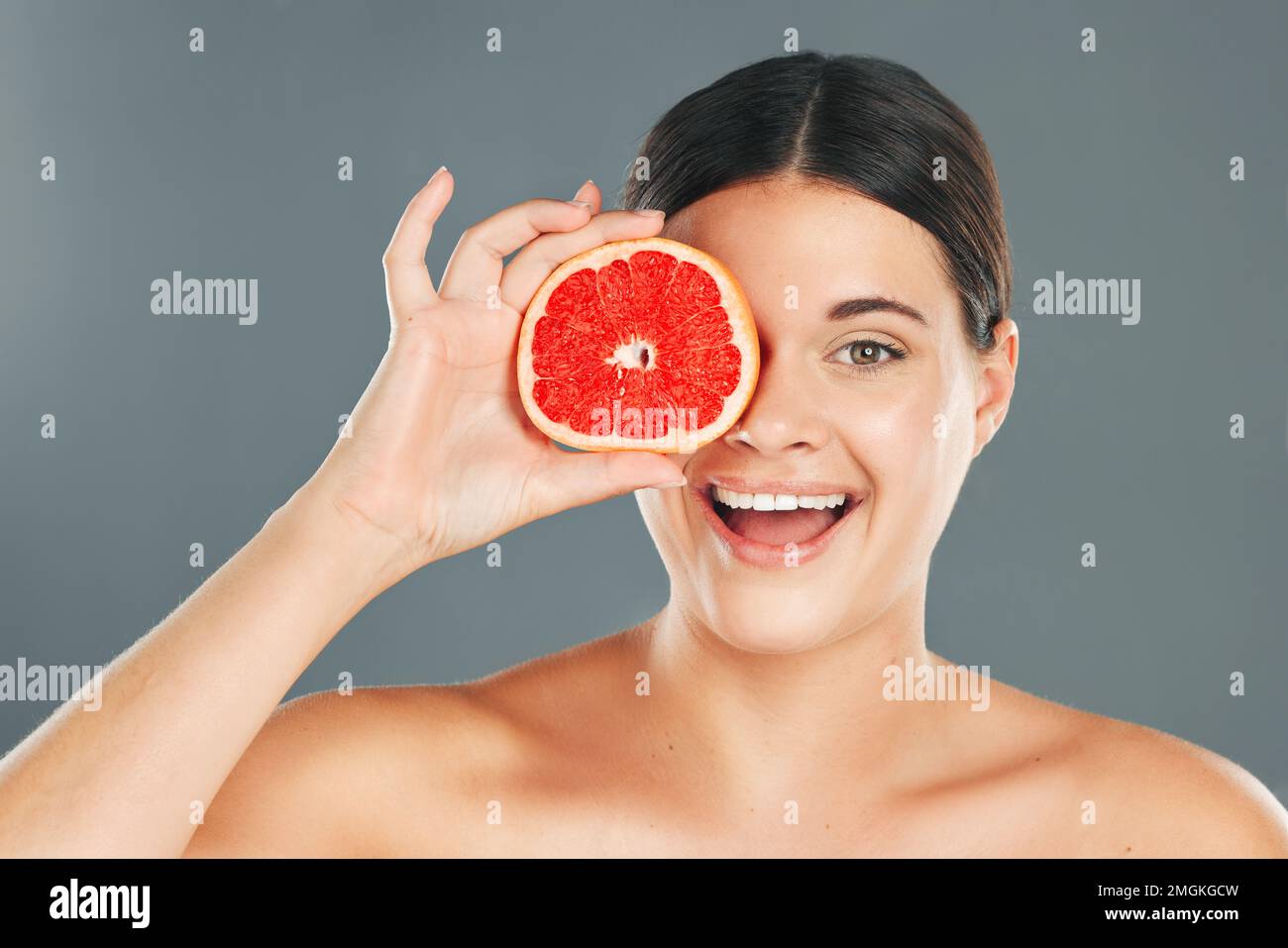 Pamplemousse, soin de la peau, femme ou bien-être esthétique pour une alimentation saine, des résultats heureux ou un brillant propre sur fond gris. Portrait de beauté, sourire ou fille Banque D'Images