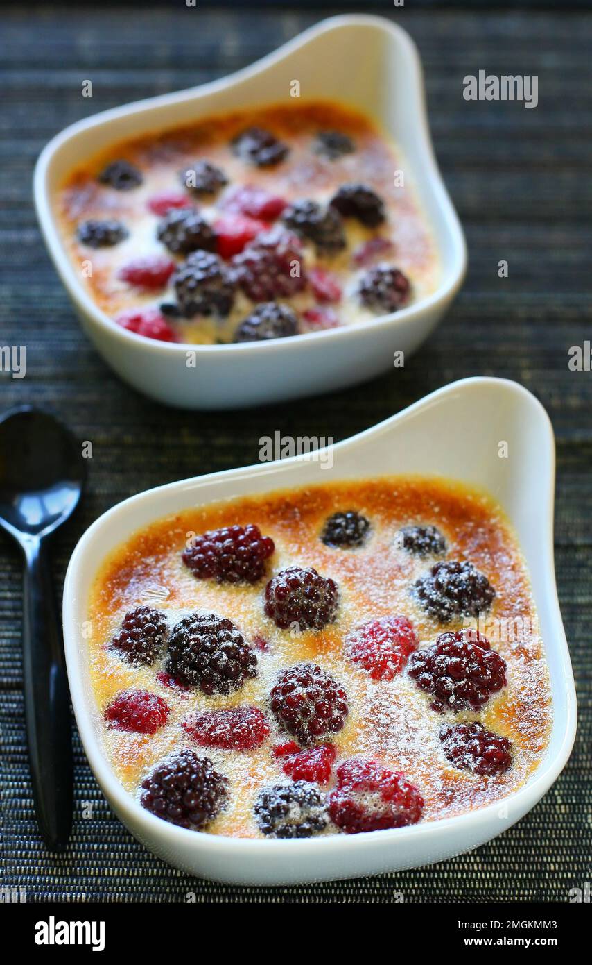 Gratin de fruits avec baies, framboises, mûres et crème dans des plats blancs sur la table pour le dessert Banque D'Images