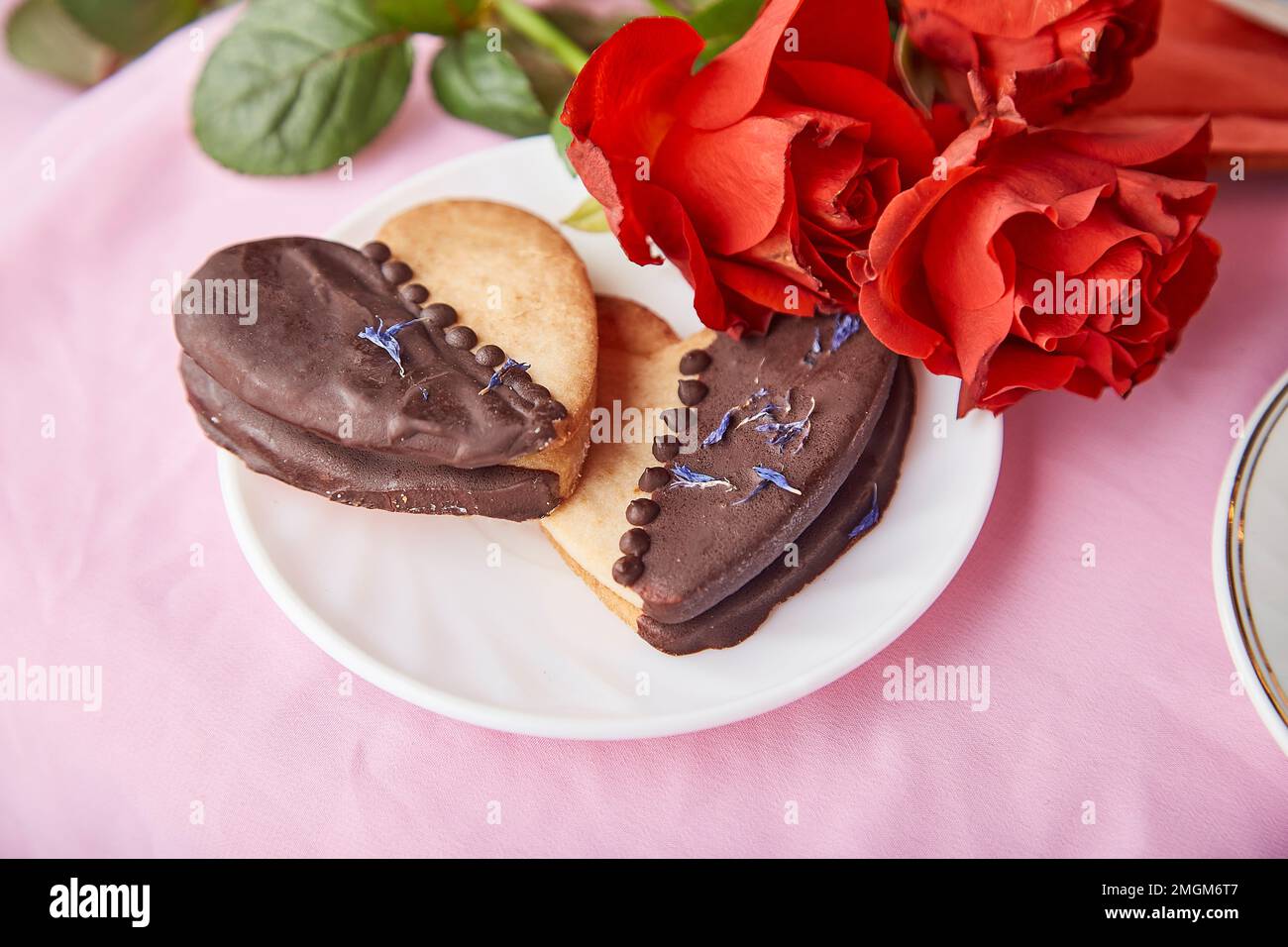 Biscuits végétaliens avec caillé orange en forme de coeur. Roses rouges esthétiques, romantique Saint Valentin biscuits. Fond de vacances rose Lagom. Repas de vacances. Banque D'Images