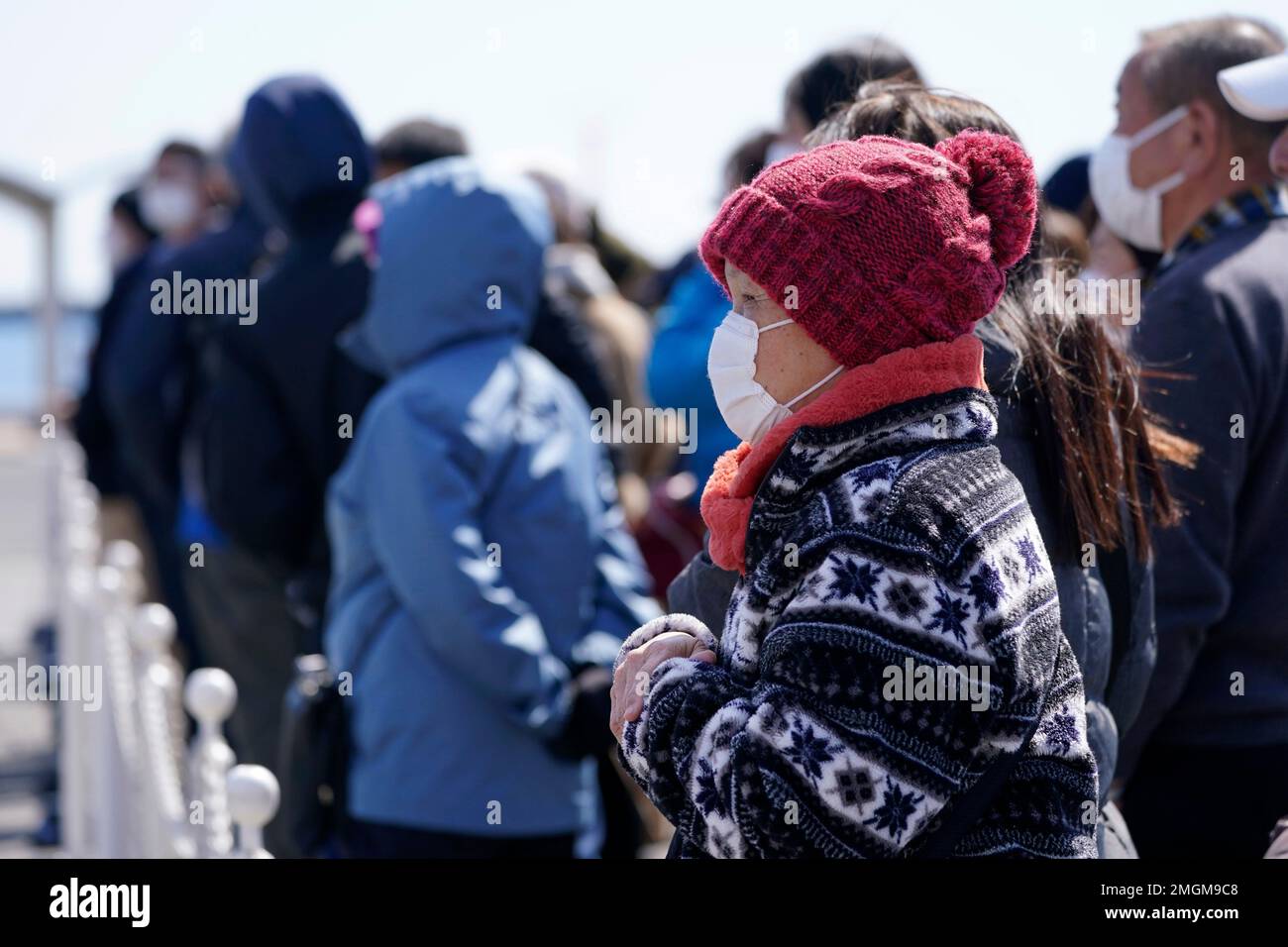 Masked spectators line up to observe the Olympic Flame burning prior to a flame display ceremony in Iwaki, Fukushima Prefecture, northern Japan, Wednesday, March 25, 2020. IOC President Thomas Bach has agreed "100%" to a proposal of postponing the Tokyo Olympics for about one year until 2021 because of the coronavirus outbreak, Japanese Prime Minister Shinzo Abe said Tuesday. (AP Photo/Eugene Hoshiko) Banque D'Images