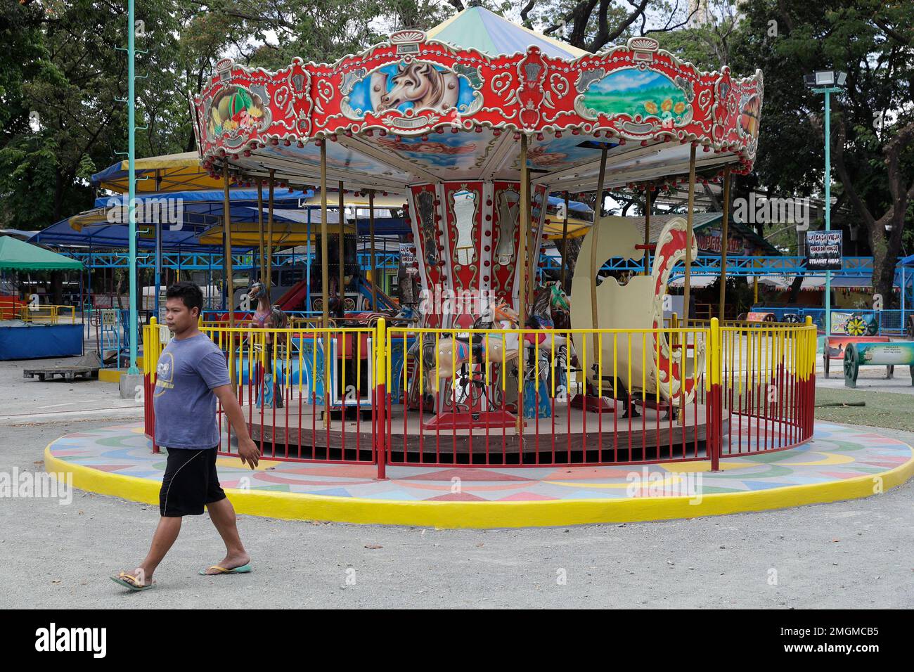 A man walks inside at an empty amusement park inside the Quezon Memorial Circle following the enhanced community quarantine enforced by the government to prevent the spread of the new coronavirus in suburban Quezon city, Philippines on Tuesday, March 24, 2020. For most people the new coronavirus causes only mild or moderate symptoms, but for some it can cause more severe illness. (AP Photo/Aaron Favila) Banque D'Images