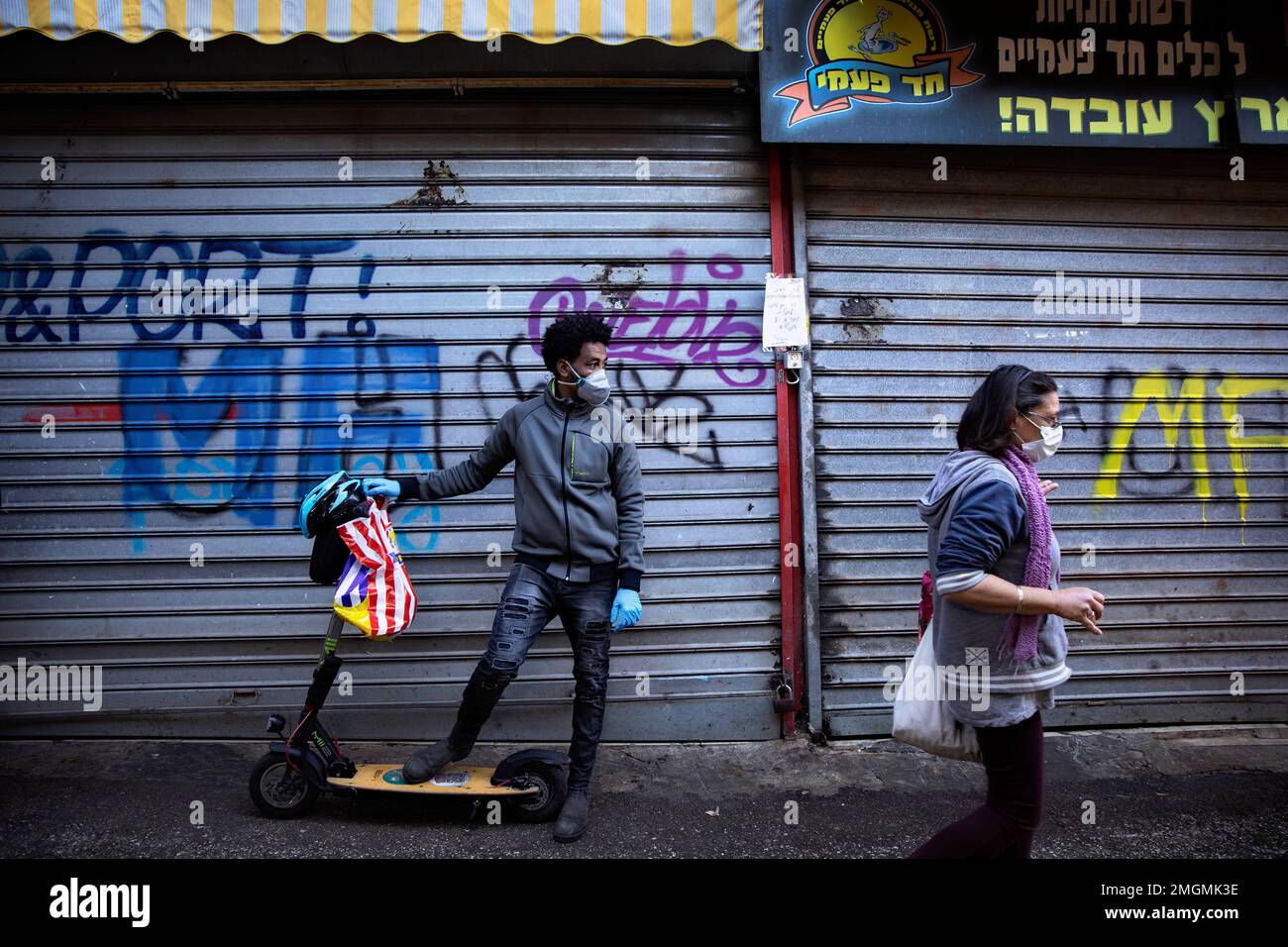 People wear face masks at a closed food market, in Tel Aviv, Israel, Sunday, March 22, 2020. Police officers ordered owners to shut down their shops at the food market in order to reduce the spread of the coronavirus. (AP Photo/Oded Balilty) Banque D'Images