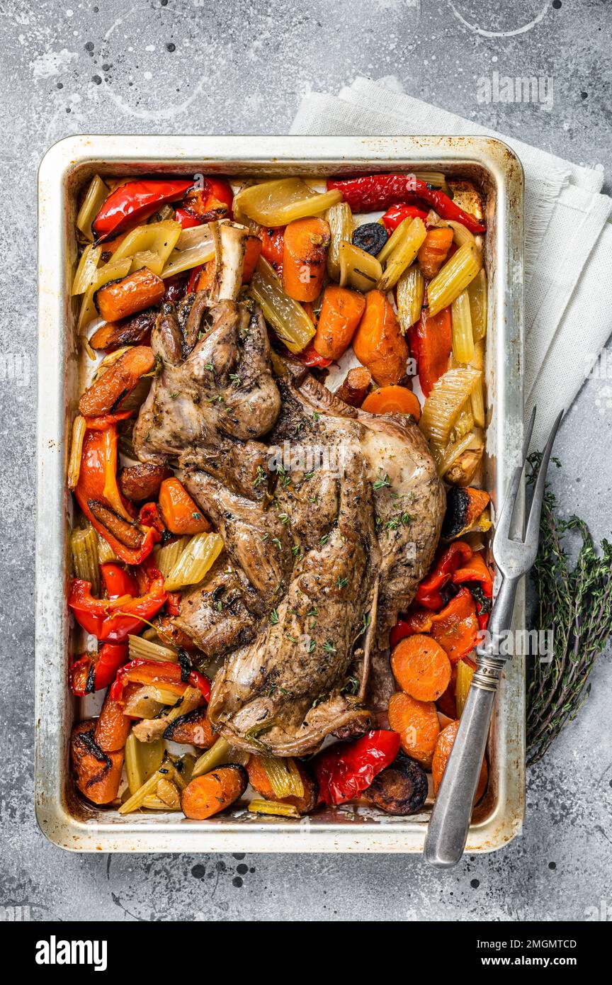 Rôti de viande d'épaule de mouton d'agneau dans un plat de cuisson avec des légumes. Arrière-plan gris. Vue de dessus Banque D'Images