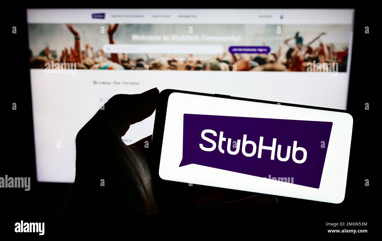 Personne tenant un téléphone portable avec le logo de la société de billetterie américaine StubHub à l'écran en face de la page Web d'affaires. Mise au point sur l'affichage du téléphone. Banque D'Images