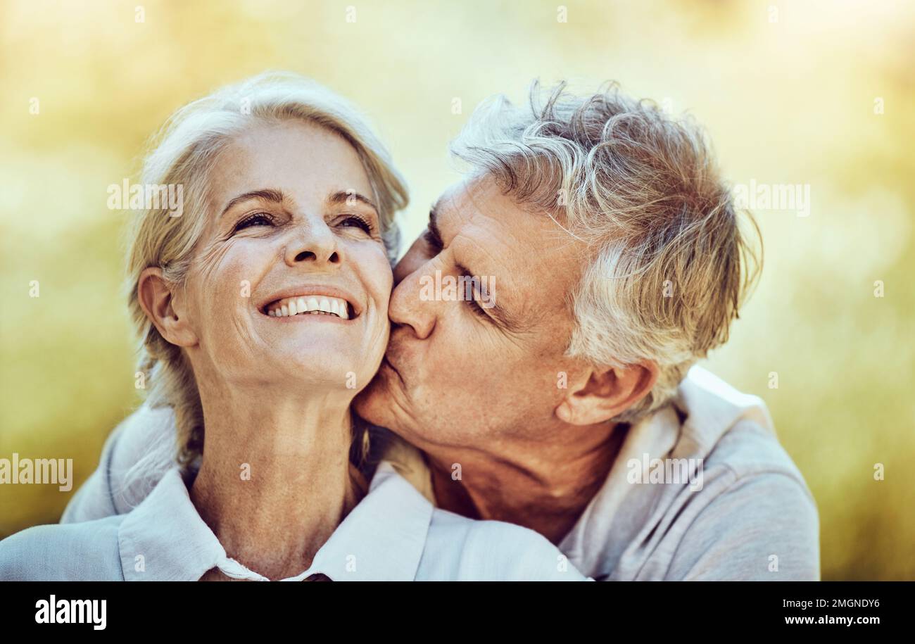 Couple senior, baiser et joue avec le sourire pour l'amour, le romantisme et s'embrasser ensemble dans la nature en plein air. Bonne femme âgée et homme embrassant le visage pour Banque D'Images