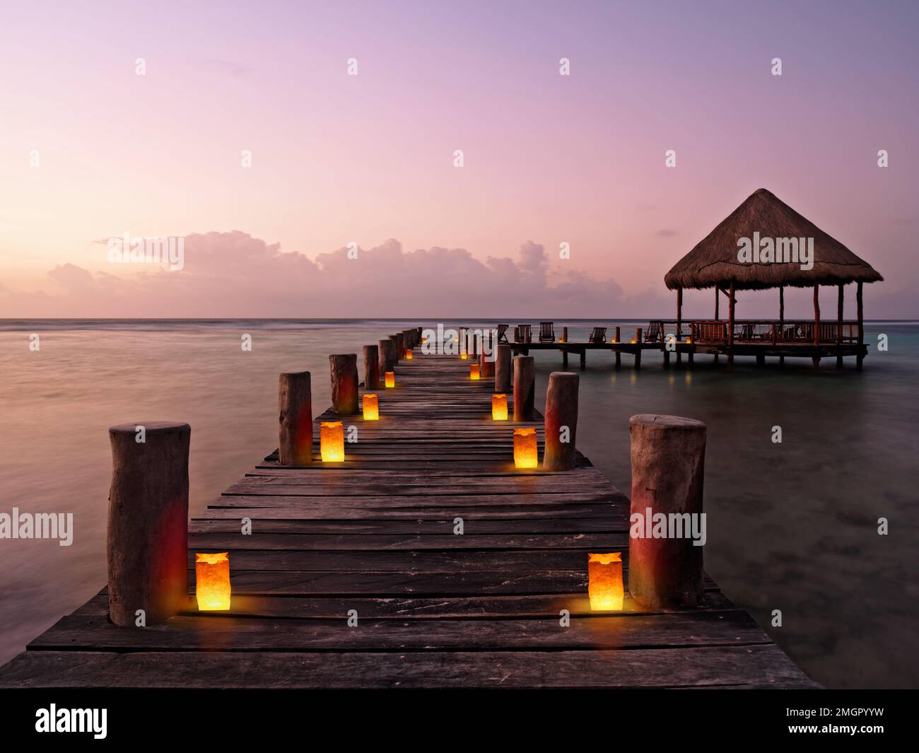 Mexique, Akumal, jetée avec palapa au crépuscule bordée de lanternes en papier illuminées Banque D'Images
