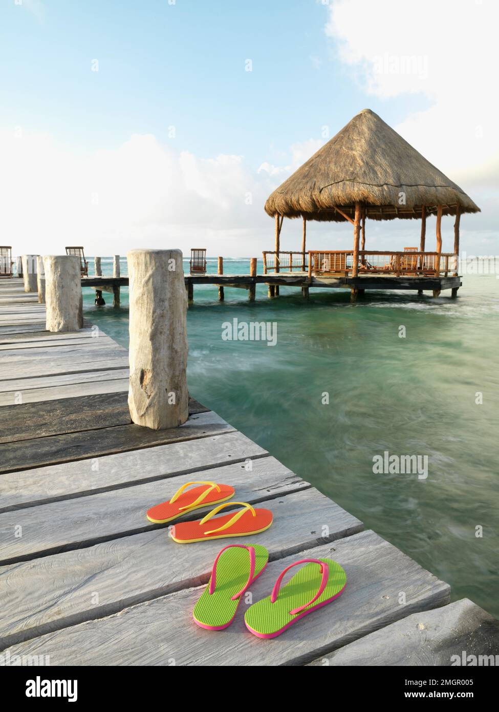 Mexique, Akumal, sandales à bascule sur une jetée avec une palapa dans le fond Banque D'Images