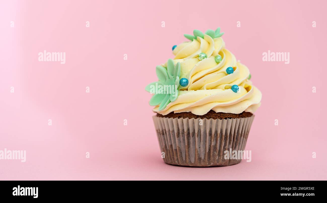 Cupcake d'anniversaire avec une décoration de fleur en massepain colorée sur fond rose Banque D'Images