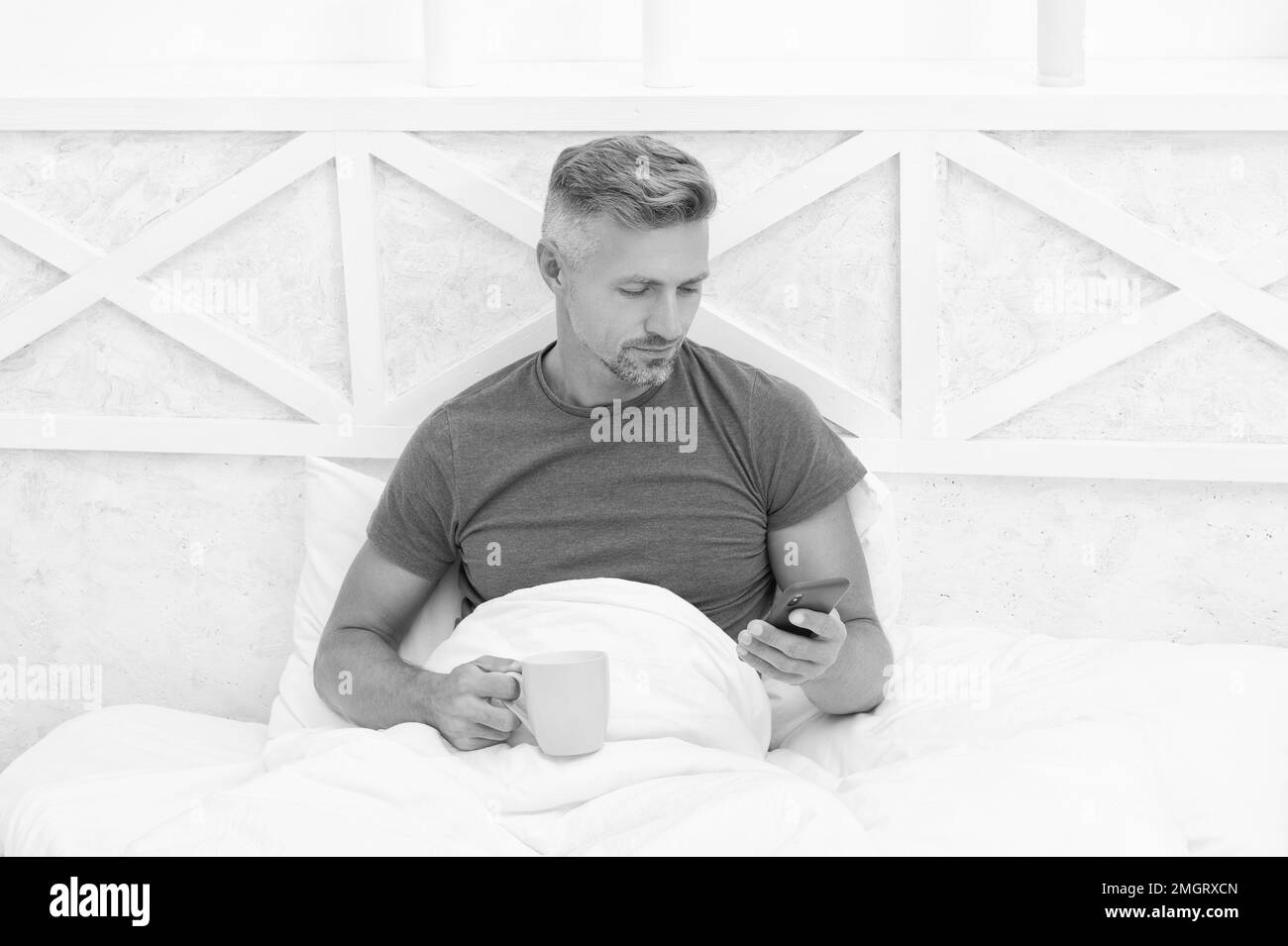 Messagerie texte mobile. Un homme éveillé envoie un message texte dans le lit. Messagerie à partir d'un smartphone. SMS Banque D'Images