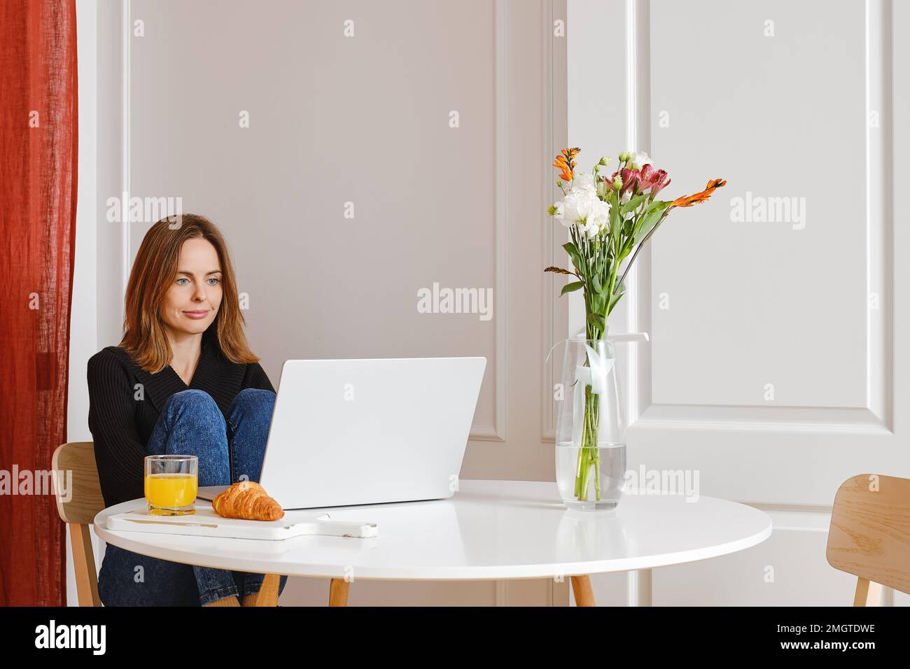 Jolie femme regardant un film sur un ordinateur portable dans son appartement Banque D'Images