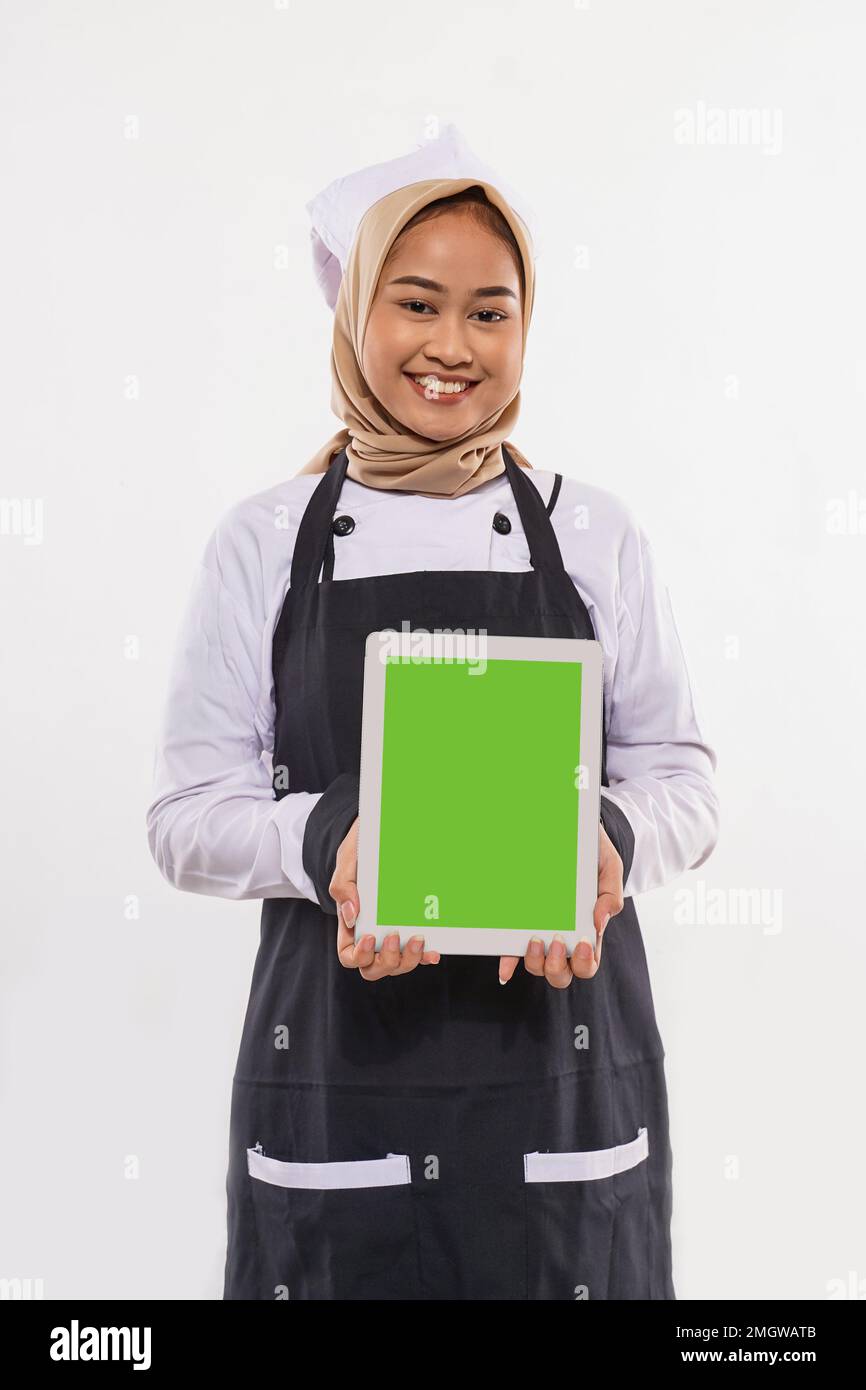 une belle cuisinière avec hijab montrant la tablette devant elle Banque D'Images
