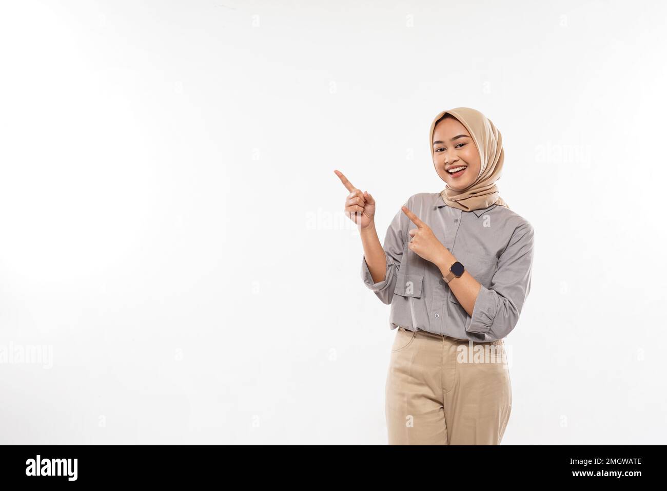 femme avec hijab pointant avec enthousiasme sur l'espace vide à ses côtés Banque D'Images