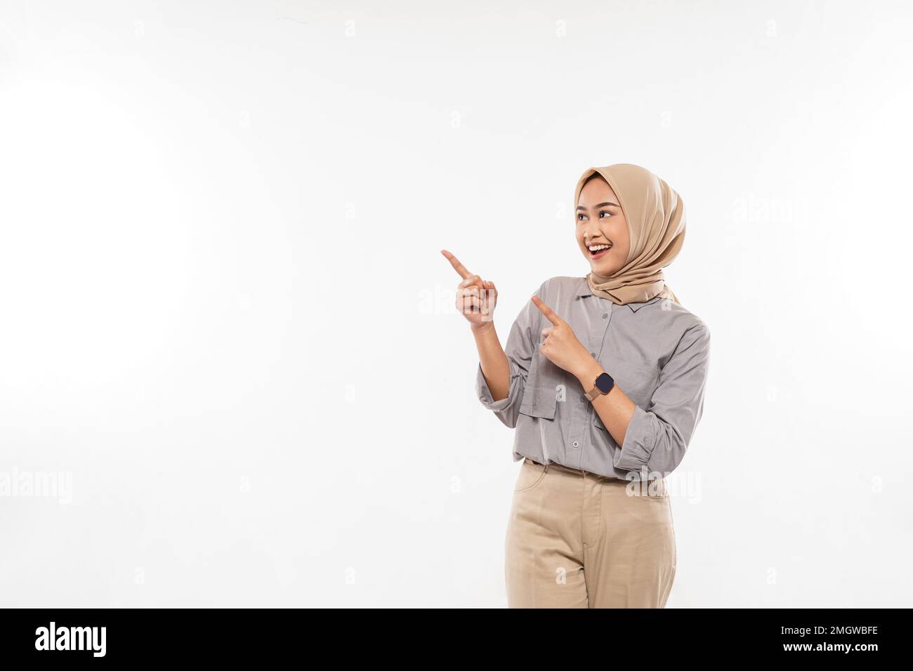 femme avec hijab pointant avec enthousiasme sur l'espace vide à ses côtés Banque D'Images