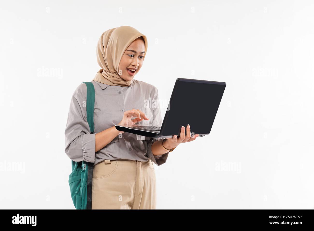 un bel étudiant avec hijab choqué tout en ouvrant l'ordinateur portable Banque D'Images