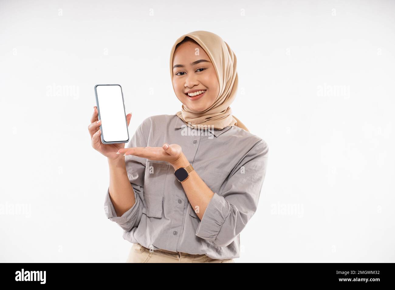 une femme en voile marron debout avec le sourire et montrant le téléphone Banque D'Images