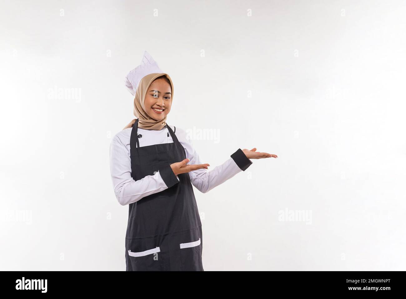 une jeune cuisinière avec hijab pointant sur son côté gauche Banque D'Images