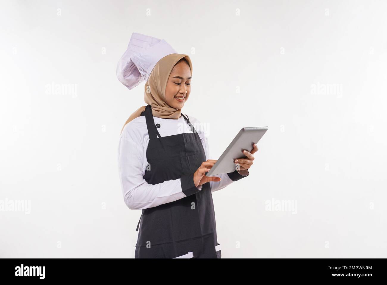un beau cuisinier avec hijab regardant la tablette Banque D'Images