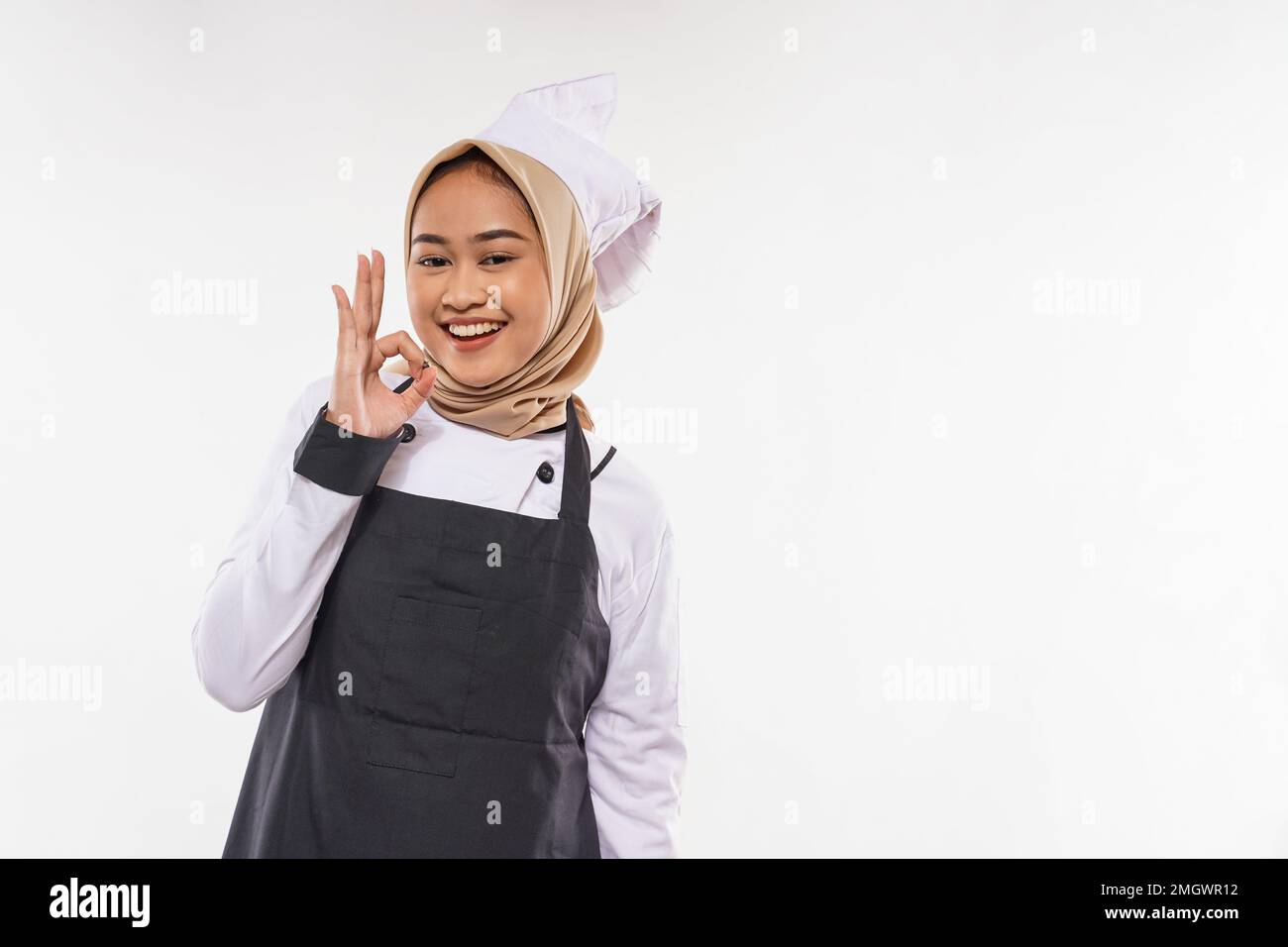 un beau cuisinier avec hijab debout avec le geste de la main d'oke et sourire Banque D'Images