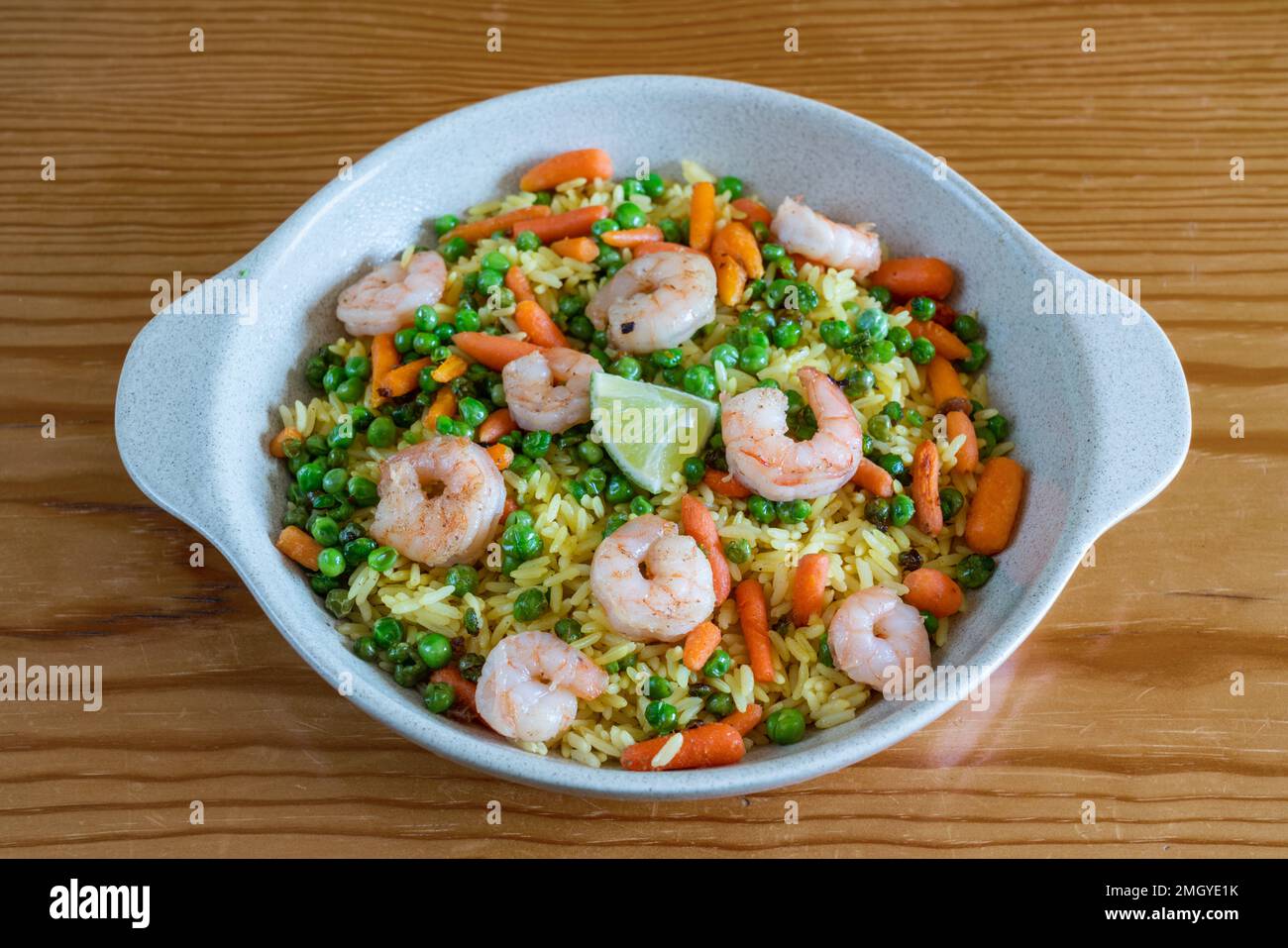 Salade orientale appétissante de calmar bouilli, de riz, de pois verts et d'autres ingrédients sur une assiette sur fond de bois. Banque D'Images