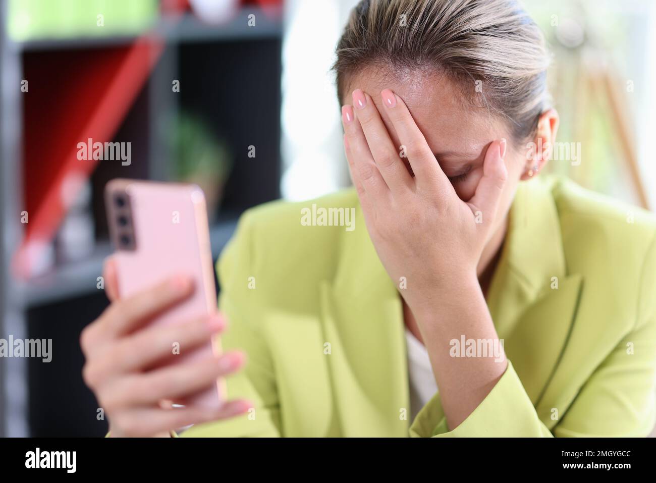Triste femme d'affaires tient le smartphone dans sa main et couvre son visage avec sa main. Banque D'Images
