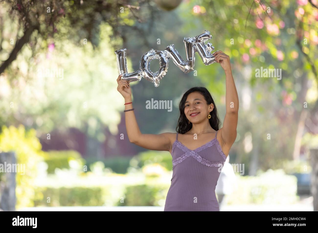 Brunette mexicaine tenant des lettres de ballon d'amour, jour de femme, concept d'amour de soi Banque D'Images