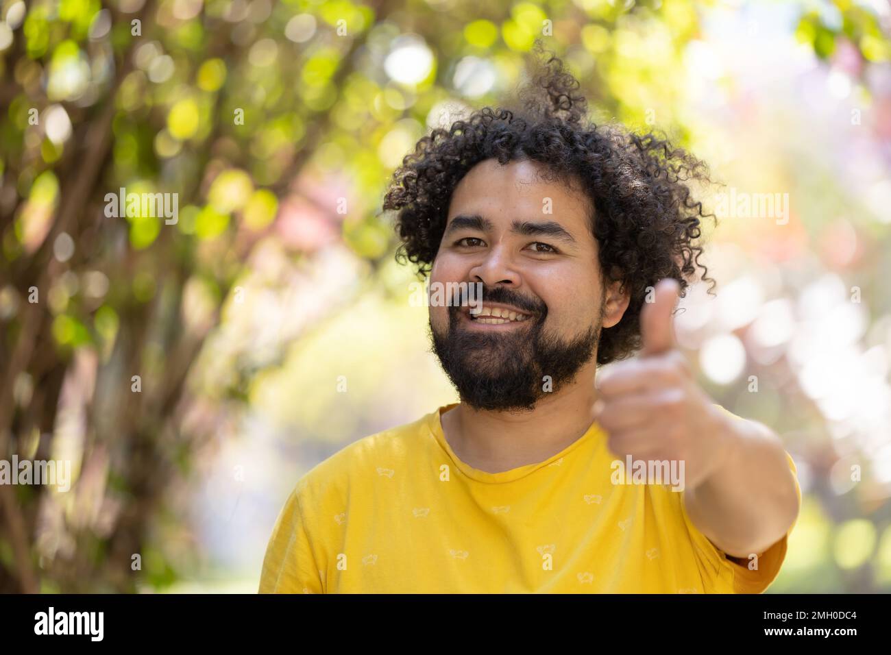 Portrait d'un homme mexicain souriant avec des cheveux bouclés et des pouces de barbe Banque D'Images