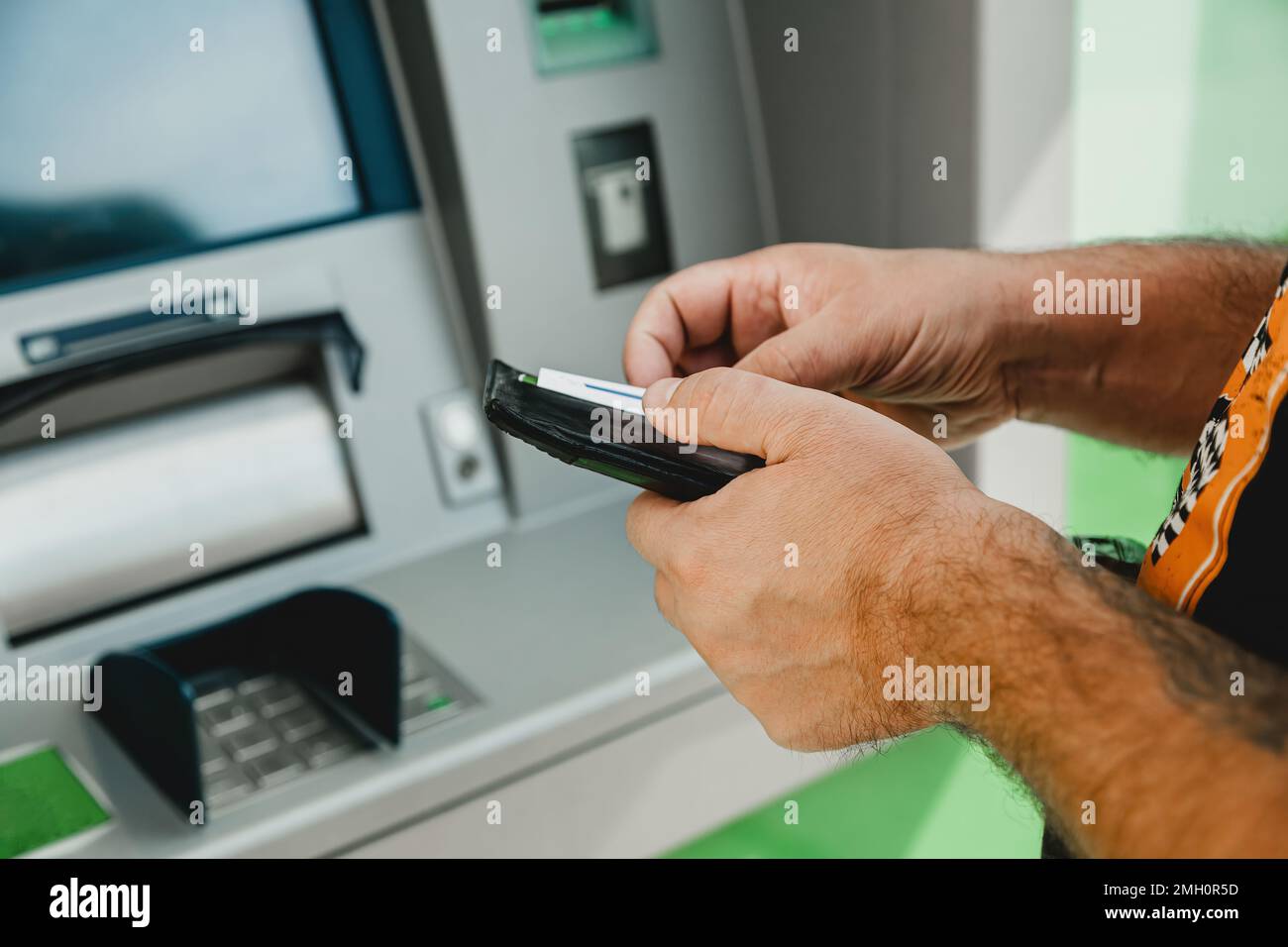 Carte ATM MAN. Carte d'insertion ATM. Homme mettant la carte de crédit dans le distributeur automatique de billets tout en tenant le portefeuille Banque D'Images