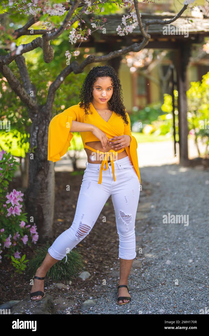 Belle jeune femme afro-américaine jouant autour sous le cerisier en fleur dans un jardin de style japonais - Printemps - Springtime Banque D'Images