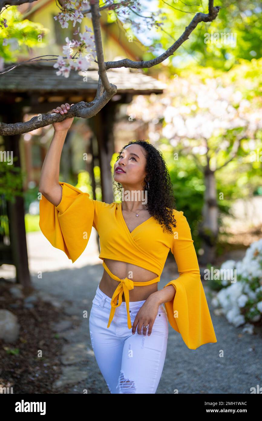 Face à la face 3/4 Portrait de corps de la jeune femme afro-américaine debout sur le chemin de terre dans le jardin de style japonais - printemps Banque D'Images