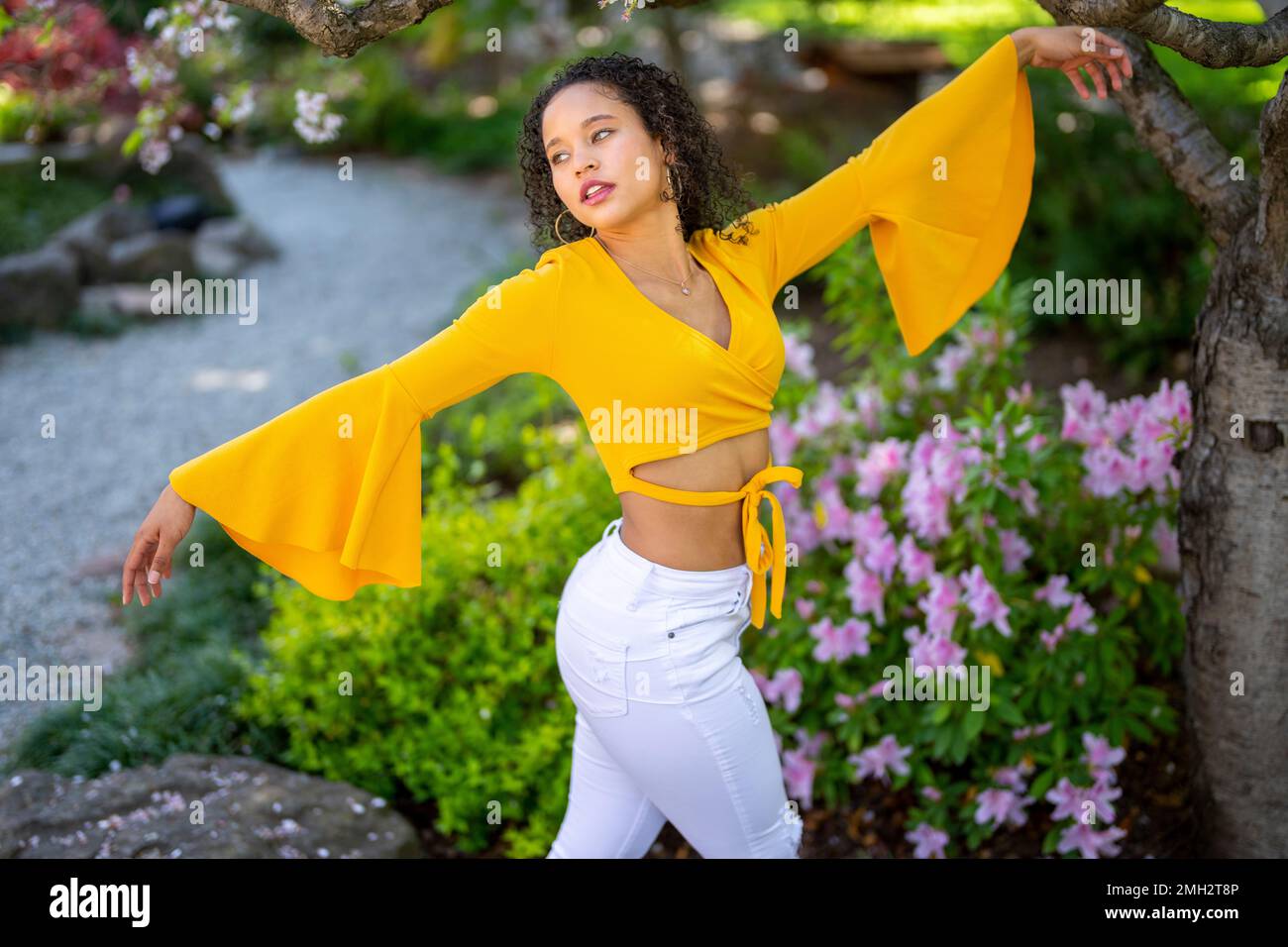 Vue latérale 3/4 Portrait de la jeune femme afro-américaine avec des armes dans le jardin de style japonais au printemps Banque D'Images