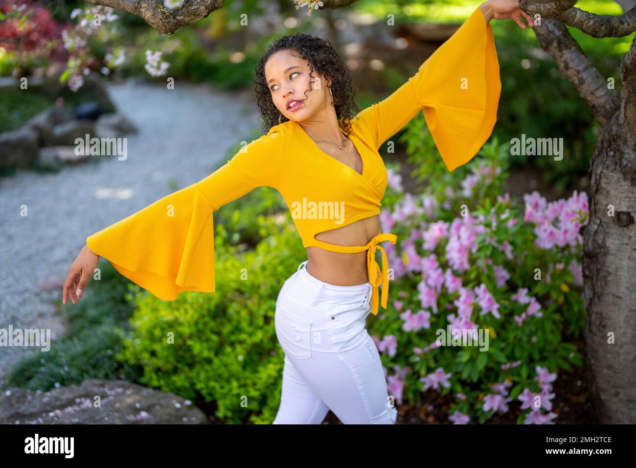 Vue latérale 3/4 Portrait de la jeune femme afro-américaine avec des armes dans le jardin de style japonais au printemps Banque D'Images