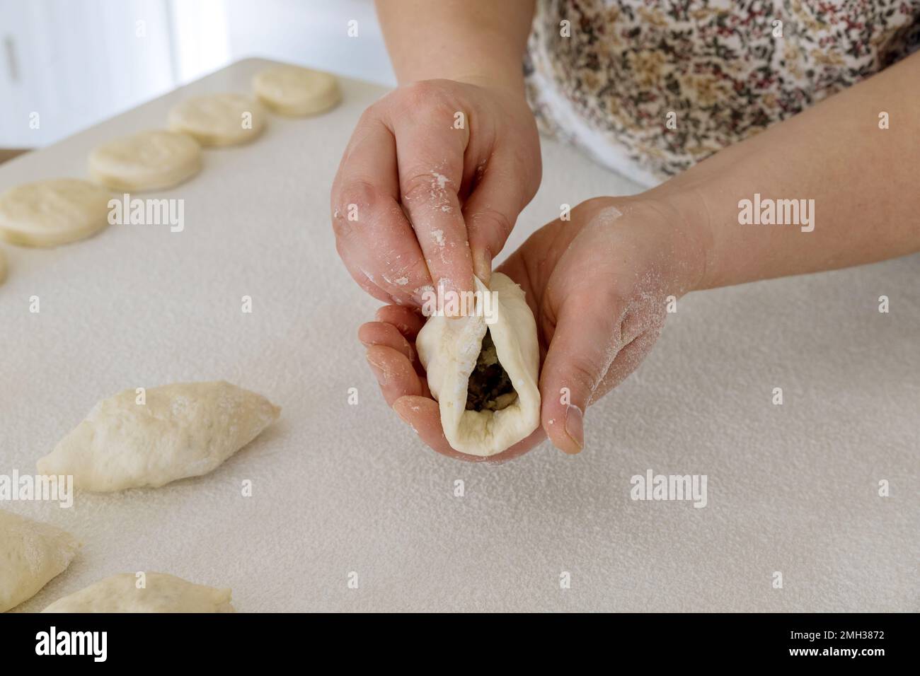 Faire des petits pains faits maison avec des pommes de terre à partir de pâte de levure sur un comptoir blanc dans la cuisine Banque D'Images
