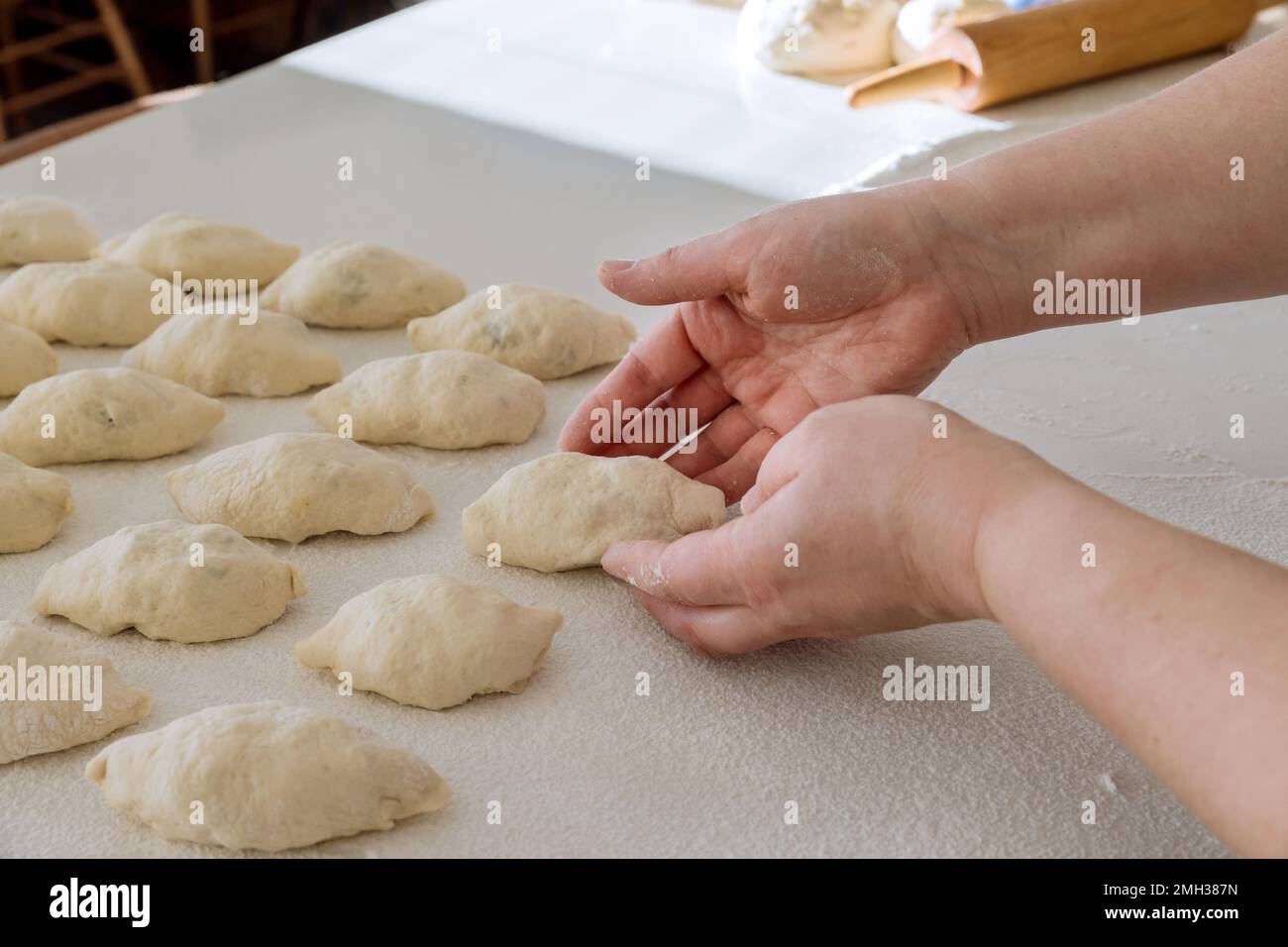 La pâte à levure est faite maison petits pains remplissant les pommes de terre sur un comptoir blanc. Banque D'Images
