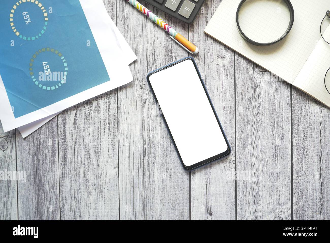 smartphone avec écran vide et tableau financier sur la table Banque D'Images