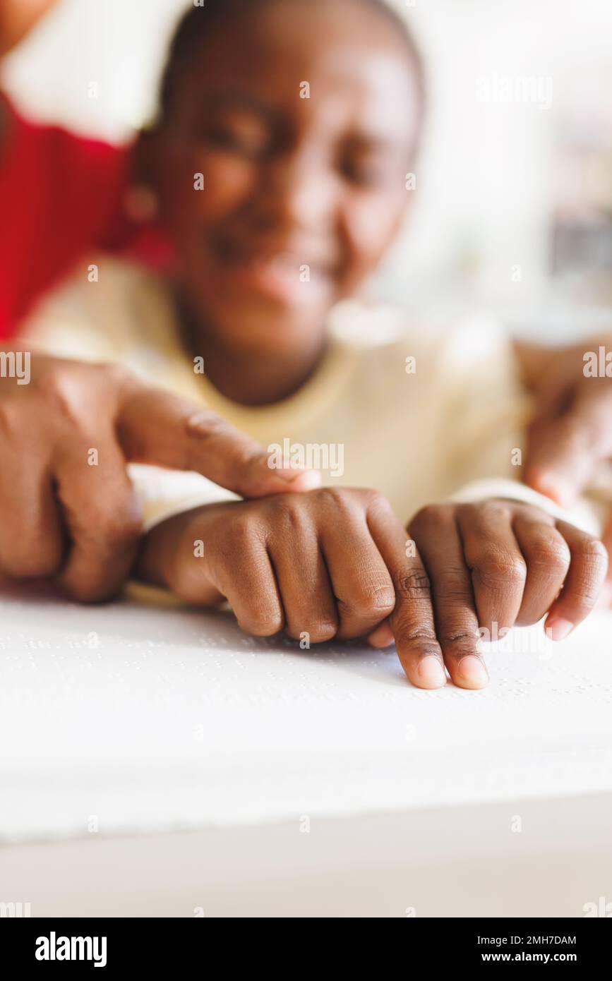 Bonne grand-mère afro-américaine et petite-fille aveugle lisant le braille Banque D'Images