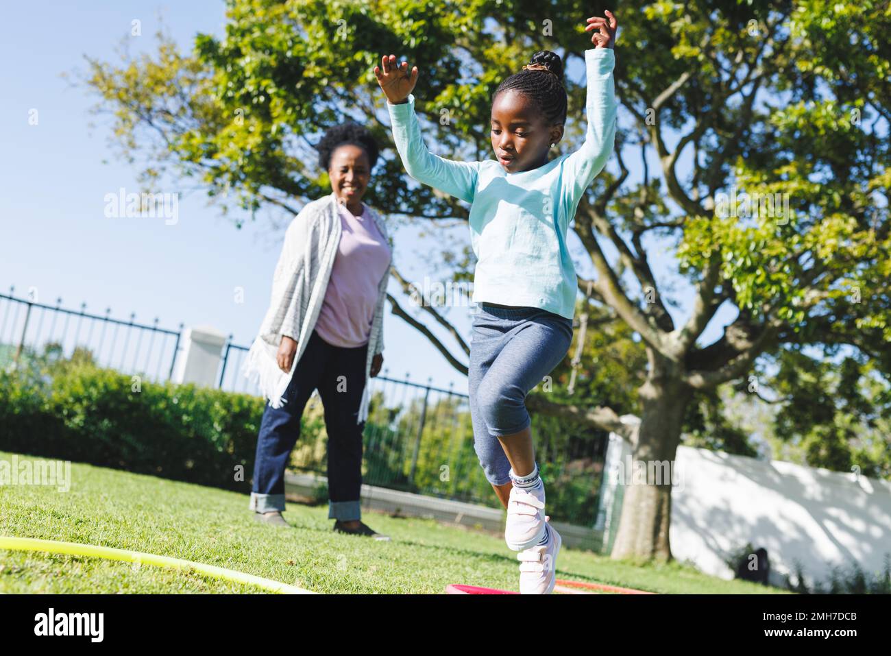 Bonne grand-mère afro-américaine et petite-fille utilisant la hula houle dans le jardin Banque D'Images