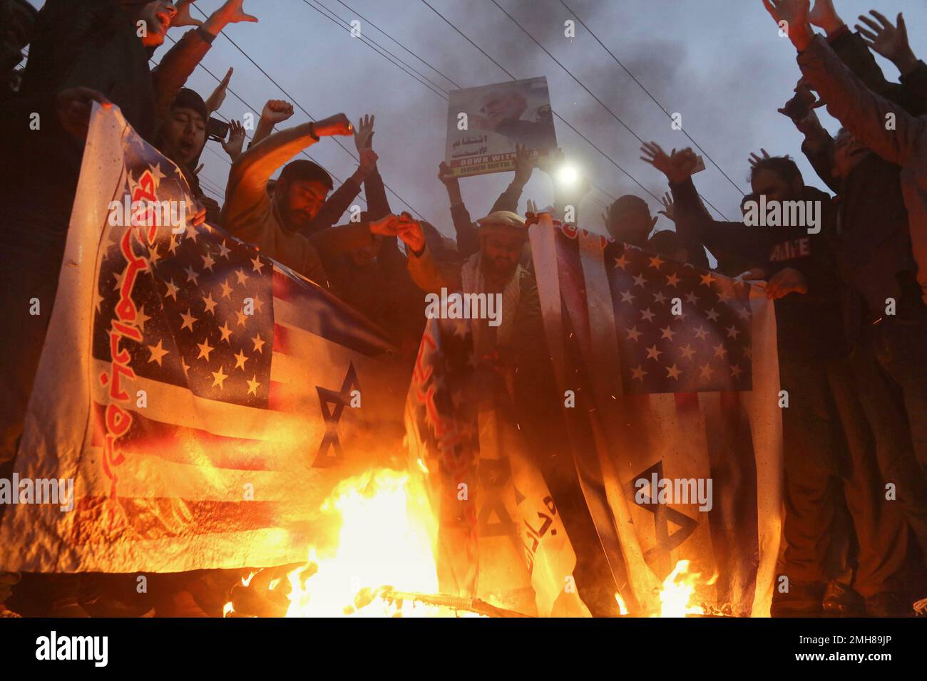 Pakistani Shiite Muslims burn representations of Israeli and U.S. flags during a rally in protest of the recent U.S. attack in Iraq that killed Iranian Gen. Qassem Soleimani, outside the U.S. Consulate in Lahore, Pakistan, Tuesday, Jan. 7, 2020. (AP Photo/K.M. Chaudary) Banque D'Images