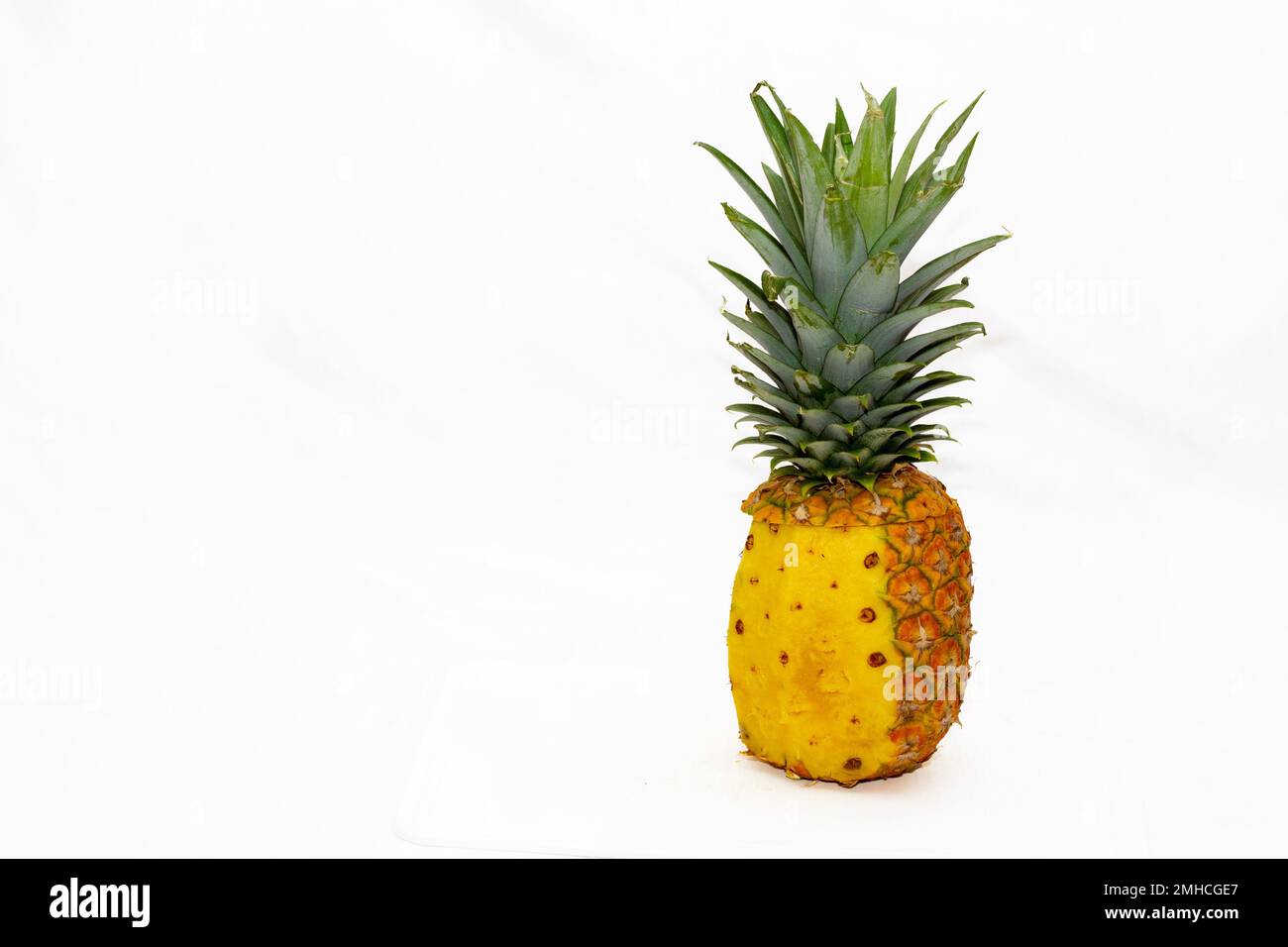 ananas avec pelure à moitié pelée sur fond blanc Banque D'Images