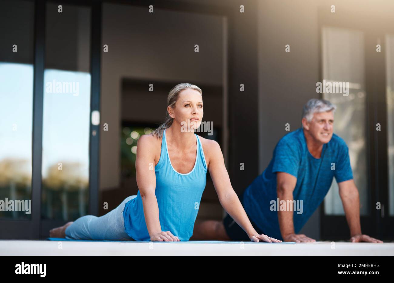 Commencez notre journée par une séance de yoga très nécessaire. Prise de vue en longueur d'un couple mature et heureux faisant des exercices de yoga à l'extérieur de leur maison. Banque D'Images