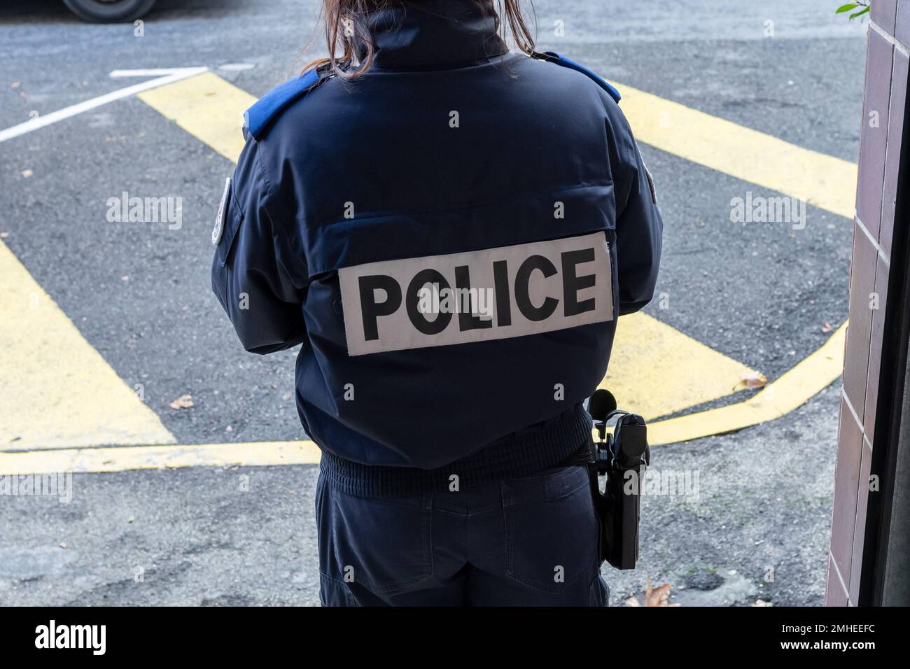 Toulon, France. 24th janvier 2023. Une policier est vue de derrière avec le  mot police sur son gilet pare-balles et une arme à la ceinture au poste de  police central de Toulon (