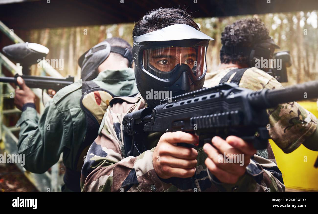 Hommes, travail d'équipe ou pistolet à paintball dans l'arène de jeux, compétition ou défi sportif en uniforme militaire. Soldats, armée ou personnes et peinture de tir Banque D'Images