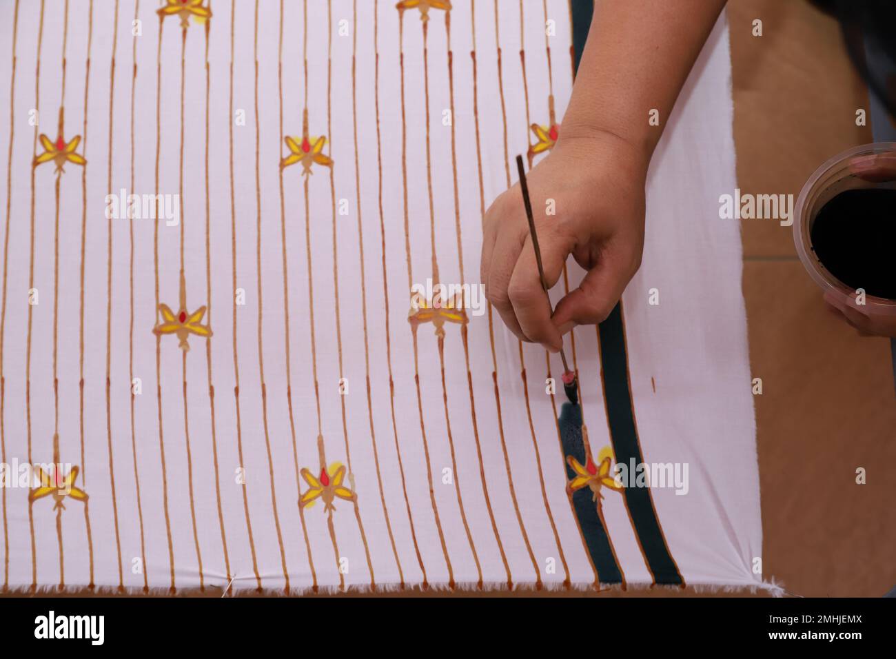 Une femme fait des croquis à la main avec des outils de cantage et de la cire chaude pour faire Batik traditionnel Banque D'Images