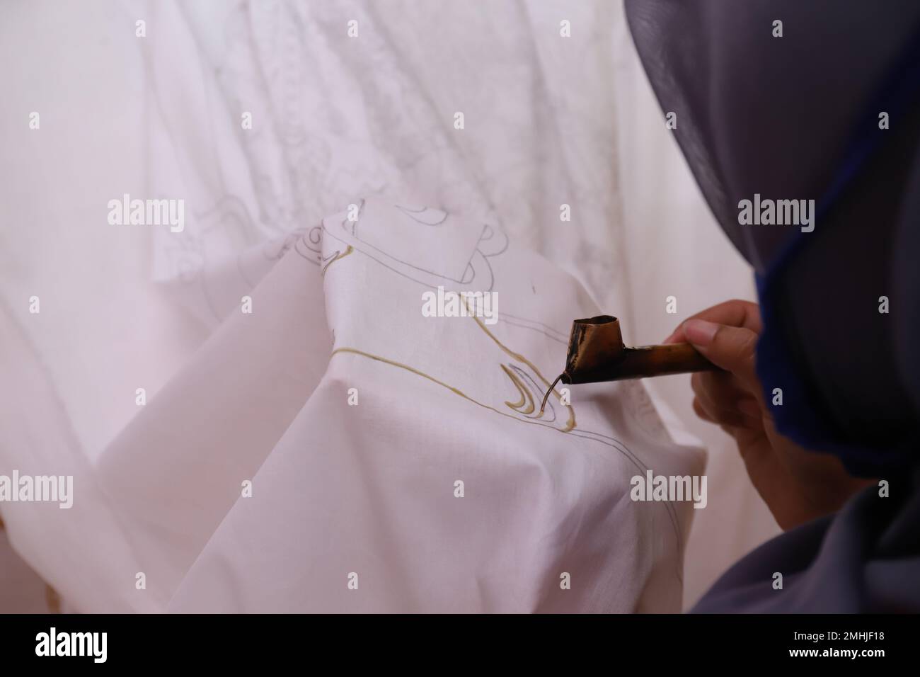 Une femme fait des croquis à la main avec des outils de cantage et de la cire chaude pour faire Batik traditionnel Banque D'Images