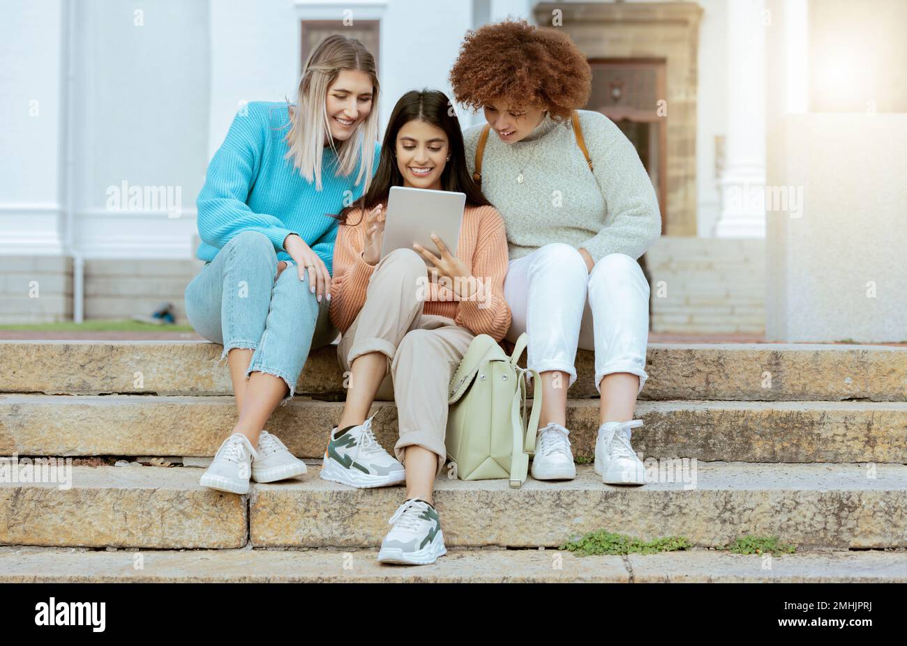Étudiants, amis et tablettes dans les escaliers des médias sociaux, de la communication ou du divertissement en streaming sur le campus. Des femmes heureuses appréciant la recherche en ligne, le chat Banque D'Images