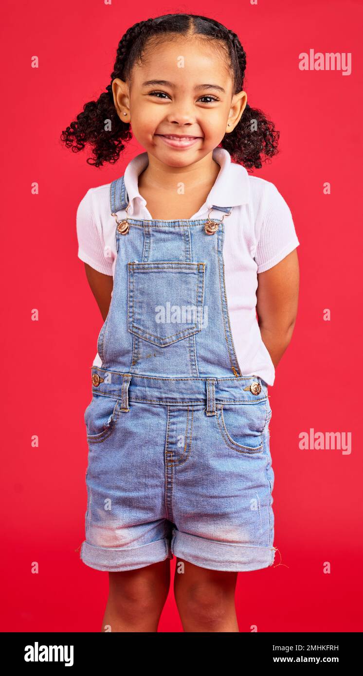 Enfant, petit et portrait de fille en studio, heureux et sourire sur fond rouge avec maquette. Visage, gai et tendance tout-petit debout contre l'espace Banque D'Images