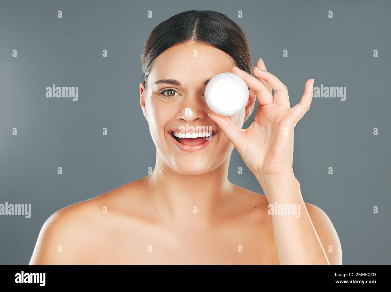Femme appliquez la crème pour le visage avec le bonheur et le portrait de beauté, les soins de la peau et l'hydratant isolés sur le fond de studio. Crème solaire, lotion et santé Banque D'Images