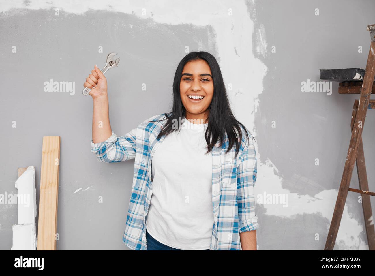 Bonne jeune femme indienne tient la clé pendant les rénovations de projet de bricolage à la maison Banque D'Images