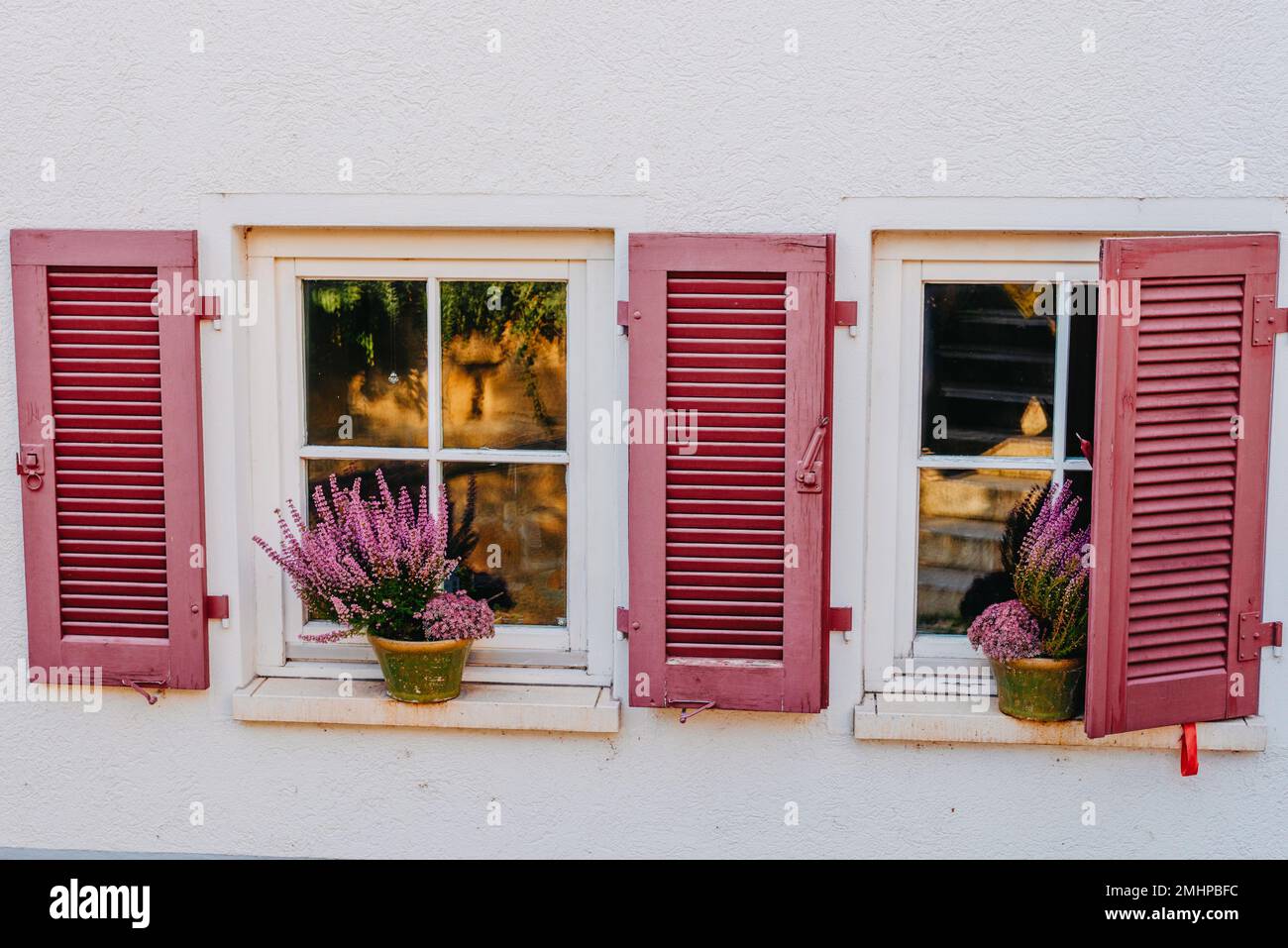 Façade typique de l'ancienne maison rétro provençale avec fenêtres et volets en bois décorés de fleurs fraîches colorées. bouganville aux fleurs violettes Banque D'Images