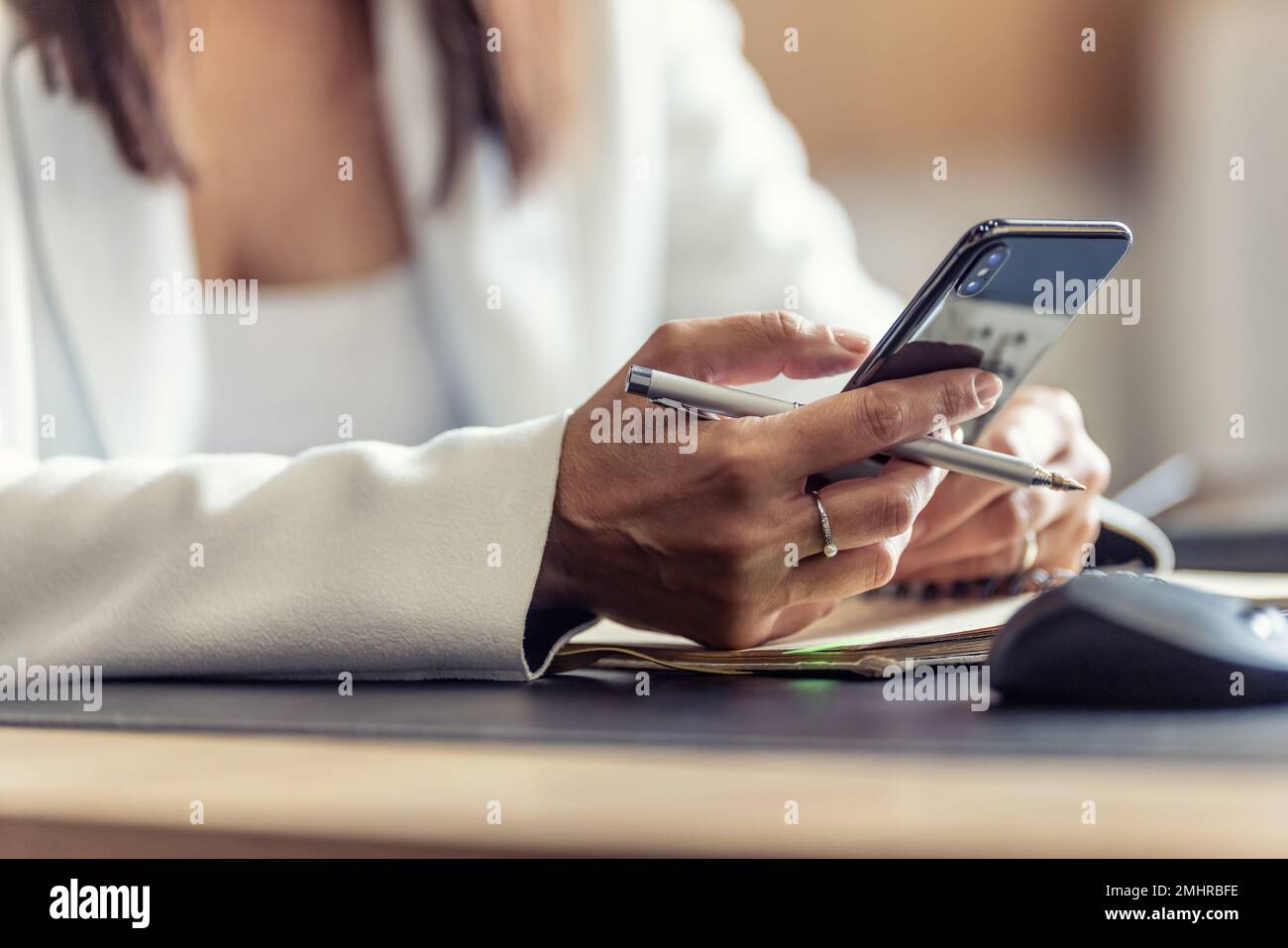 Mains d'une femme responsable avec un téléphone mobile, communiquant avec ses collègues pendant les heures de travail, envoyant des messages ou recevant des informations professionnelles. Banque D'Images